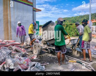 Puerto Galera, Philippines - 9 avril 2022: Une équipe de travailleurs philippins utilisant un mélangeur de béton portable sur un chantier de construction sur l'île Mindoro. Banque D'Images