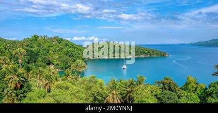 Belle scène de paysage tropical à Puerto Galera sur l'île Mindoro, Philippines, montrant un yacht ancré dans la baie d'Encenada. Banque D'Images