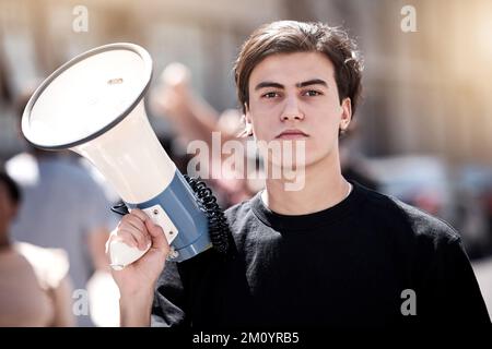 Nous ne serons pas ignorés. un jeune homme tenant un mégaphone lors d'un rassemblement de protestation. Banque D'Images