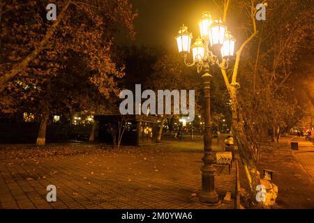 Lanterne de rue lumineuse dans un parc en soirée. Poteau lumineux avec de nombreuses lampes. Banque D'Images