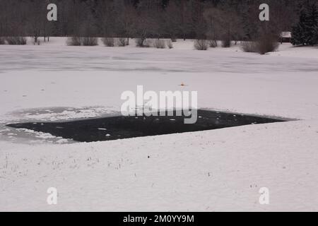 Un trou rectangulaire a été fait dans la glace épaisse couvrant un lac complètement gelé afin que le poisson puisse respirer et être nourri. Banque D'Images