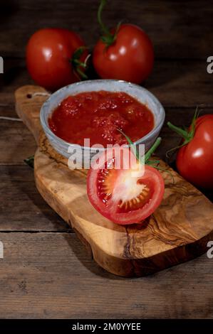 Tomates tendues dans de petits bols sur une planche à découper rustique Banque D'Images