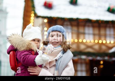 La mère et la fille se promeunent dans la ville pendant les fêtes de Noël et du nouvel an. Parent et petit enfant s'amusant à l'extérieur Banque D'Images