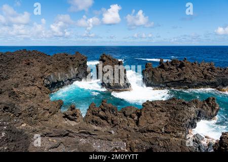 Crique d'eau claire et bleue sous les falaises volcaniques et les rochers le long de la rive dans le parc national de Waiʻanapanapa, Maui Banque D'Images