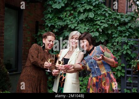 Les femmes matures fêtent et rient, tiennent des spapers et des verres de vin d'alcool ou de champagne sur la fête en plein air Banque D'Images