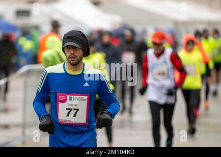 Les athlètes qui s'entraînent sous la pluie à l'occasion de la course de relais de marathon de Téléthon. Udine ville, Italie. 4 décembre 2022. Banque D'Images