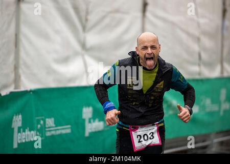 Les athlètes qui s'entraînent sous la pluie à l'occasion de la course de relais de marathon de Téléthon. Udine ville, Italie. 4 décembre 2022. Banque D'Images