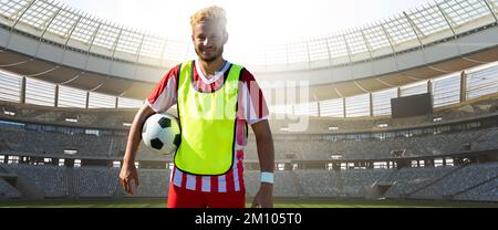 Portrait d'un jeune joueur de football biracial souriant avec ballon au stade le jour ensoleillé, espace de copie. Sport, sport de compétition, compétence, athlète, confide Banque D'Images