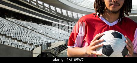 Section intermédiaire de jeune homme afro-américain joueur de football avec ballon au stade, espace de copie. Sport, sport de compétition, compétence, athlète, panoramique. Banque D'Images