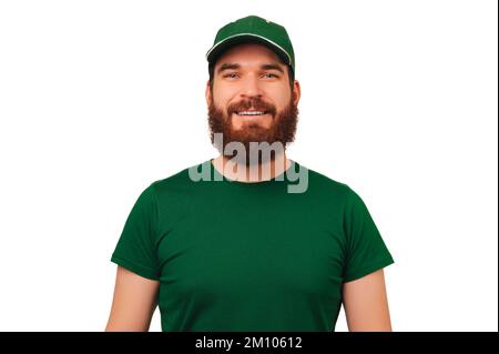 Le portrait d'un bel homme barbu porte un uniforme vert coursier avec une casquette. Banque D'Images