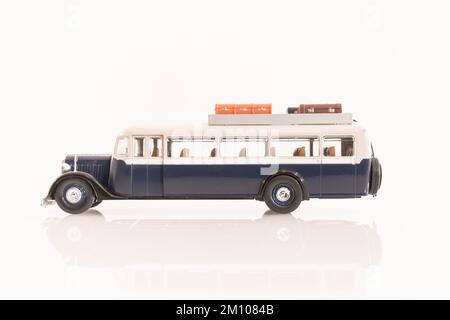 Véhicule miniature de bus ancien avec bagages sur le toit en métal bleu et blanc. Banque D'Images