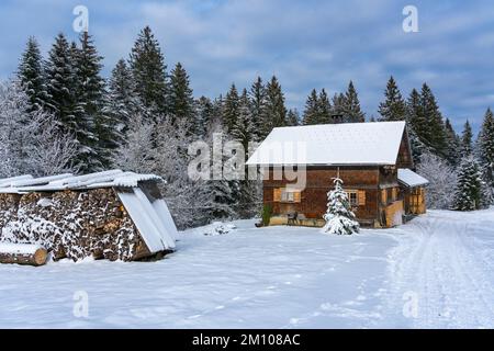 Holzhaus, Ferienhaus am Waldrand auf dem Hügel im ersten Schnee, verschneite Landschaft mit weißen Wiesen und Bäumen. Avent und Weihnachtszeit Ferien Banque D'Images