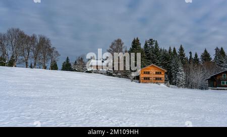 Holzhaus, Ferienhaus am Waldrand auf dem Hügel im ersten Schnee, verschneite Landschaft mit weißen Wiesen und Bäumen. Avent und Weihnachtszeit Ferien Banque D'Images