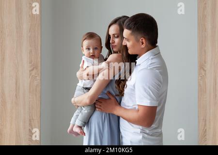 Bonne famille ensemble. Belle mère et père tenant un enfant qui regarde dans l'appareil photo. Parents, Portrait de maman, papa et fils souriants iso Banque D'Images