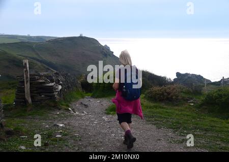 Femme seule marchant jusqu'à la station de belvédère de Willapark près de Boscastle au coucher du soleil sur le South West Coastal Path à Cornwall, Angleterre, Royaume-Uni. Banque D'Images