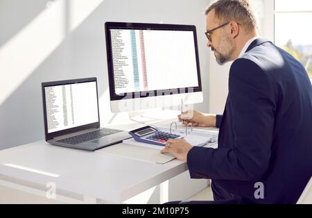 Directeur financier masculin concentré dans les travaux de bureau utilisant le logiciel de facturation électronique. Banque D'Images