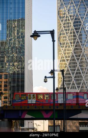 LONDRES - 4 novembre 2020: Docklands Light Railway le train DLR traverse le pont en face de bâtiments modernes de bureaux en verre Banque D'Images