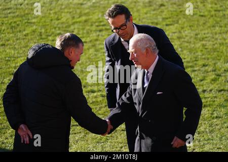 Ryan Reynolds regarde le roi Charles III parler avec le directeur Phil Parkinson au terrain de course du club de football de l'association Wrexham pour en apprendre davantage sur le réaménagement du club, dans le cadre de sa visite à Wrexham avec le Queen Consort. Date de la photo: Vendredi 9 décembre 2022. Banque D'Images