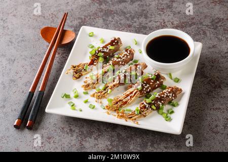 Les rouleaux de bœuf Enoki sont des hors-d'œuvre tendres et juteux faits à partir de savoureux champignons enoki enveloppés dans du bœuf finement coupé dans une assiette sur la table. Horizonta Banque D'Images