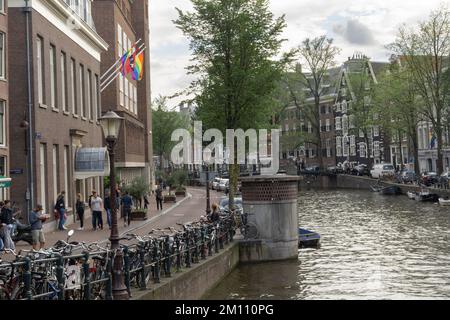 Scène touristique d'amsterdam avec vélos sur le canal de la rivière Amstel et drapeau de fierté à l'aube ensoleillée Banque D'Images