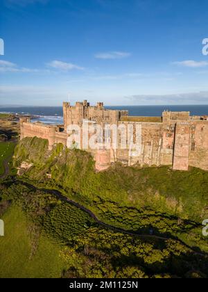 Le château de Bamburgh, l'ancienne capitale du Royaume de Northumbrie, se dresse sur la côte nord-est sous un ciel bleu vif. Le château de Bamburgh est un fort imposant et un exemple de l'architecture normande. Banque D'Images