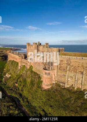 Le château de Bamburgh, l'ancienne capitale du Royaume de Northumbrie, se dresse sur la côte nord-est sous un ciel bleu vif. Le château de Bamburgh est un fort imposant et un exemple de l'architecture normande. Banque D'Images