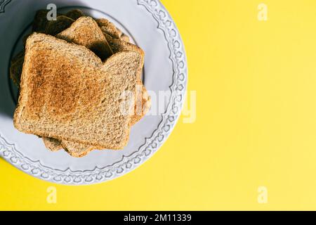 Gros plan de la plaque grise avec une tour de tranches de pain grillé sur fond jaune. Concept petit déjeuner. Vue de dessus Banque D'Images