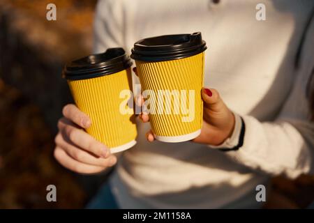 Verres avec boisson chaude dans les mains du jeune couple Banque D'Images