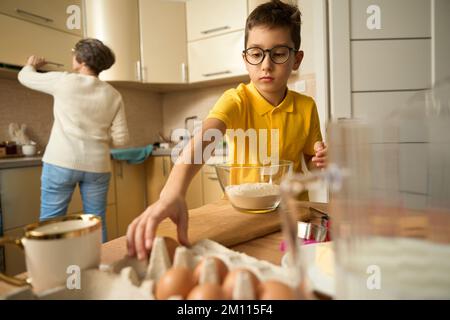 Le garçon est venu visiter la granny et préparer des pâtisseries Banque D'Images