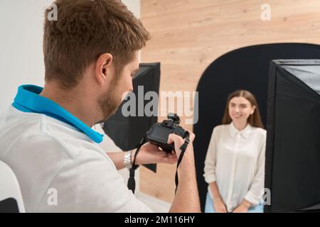 Un dentiste qui photographie un patient joyeux à l'aide d'un appareil photo numérique Banque D'Images