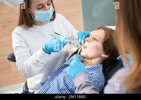 Femme dentiste au travail travaille avec des outils spéciaux Banque D'Images