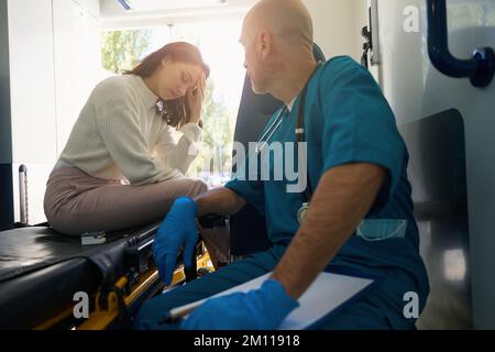 Le médecin et le patient sont assis dans une ambulance mobile Banque D'Images