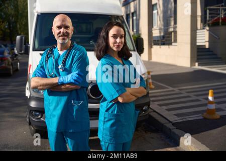 Deux employés de la brigade d'ambulance se tiennent près de la voiture de service Banque D'Images