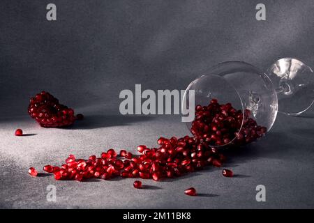 Graines de grenade dans un verre de vin et morceaux de grenade mûrs à proximité. Vin de grenade. Le concept de romance. Concept d'alimentation saine. En hiver Banque D'Images