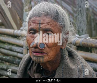 Ziro, Arunachal Pradesh, Inde - 03 04 2014 : Portrait de la vieille femme tribale d'Apatani avec des tatouages faciaux traditionnels et des prises de nez assis à l'extérieur Banque D'Images