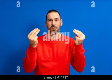 Latin homme environ 40s avec la barbe portant le cavalier rouge sur fond bleu isolé faisant le geste italien avec les mains et les doigts expression confiante. Banque D'Images