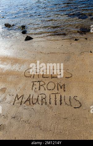 Accueil de maurice message écrit avec un doigt dans le sable sur une plage avec des vagues et bleu océan à l'île Maurice, Afrique, vue de dessus, personne Banque D'Images