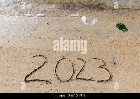 2023 comme un message écrit avec un doigt dans le sable sur une plage avec des vagues et l'océan bleu à l'île Maurice, Afrique, vue de dessus, personne Banque D'Images