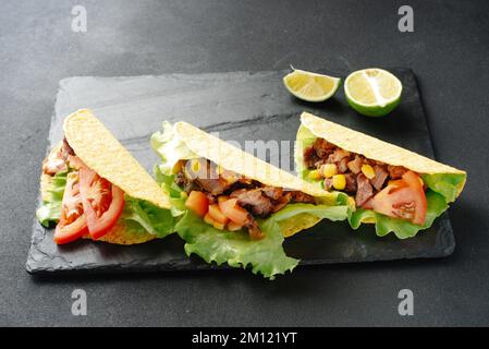 Tacos mexicains, légumes et salsa. Tacos al curé sur une planche de bois sur fond noir. Vue de dessus avec espace de copie. Banque D'Images