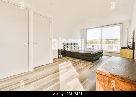 une chambre avec des murs blancs et du parquet dans la partie centrale de la chambre, il y a un grand lit Banque D'Images