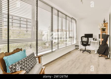 un salon avec parquet et volets blancs sur les fenêtres donnant sur un bureau Banque D'Images