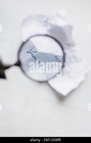 Gros plan d'une lettre déchirée avec une loupe au premier plan Banque D'Images