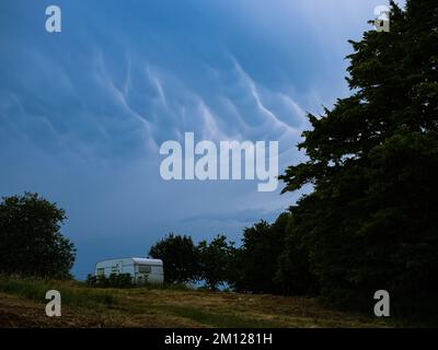 Avant une tempête, les nuages de mammatus se rassemblent au-dessus d'un champ de campeurs dans une supercellule Banque D'Images