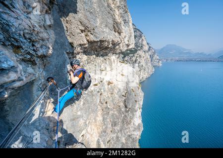 Pregasina, Riva del Garda, Trentin, Italie, Europe. Un grimpeur sur le chemin haut au-dessus du lac de Garde sur la route 'assimilano Torti', également appelé la route de Smuggler Banque D'Images