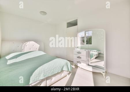 une chambre avec un lit, une commode et un miroir sur le mur en face de la chambre est très propre blanc Banque D'Images