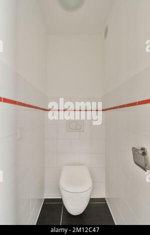 une toilette blanche dans une salle de bains avec des carreaux rouges et blancs sur le mur derrière elle est une cabine de douche ouverte Banque D'Images