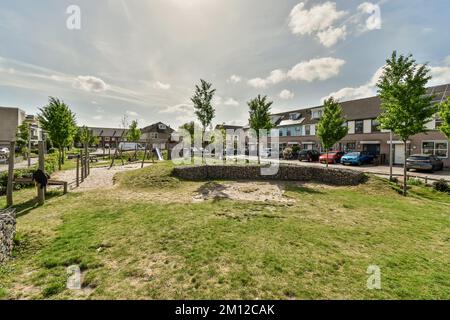 un terrain vide au milieu d'un quartier résidentiel, avec beaucoup de maisons et de voitures garées des deux côtés Banque D'Images