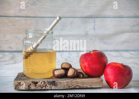 pot de miel d'abeille avec un balancier de miel sur un panneau en bois antique, atmosphère d'automne avec châtaignes et quelques pommes rouges Banque D'Images