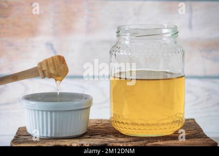 pot de miel d'abeille avec une petite tasse et un balancier de miel sur un panneau en bois antique Banque D'Images