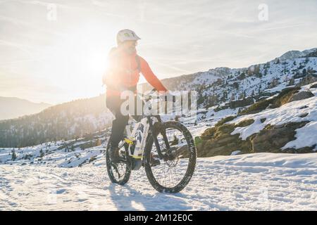 Italie, Vénétie, province de Belluno, Dolomites, cycliste à cheval sur un e-bike moderne en hiver le long d'une piste enneigée Banque D'Images